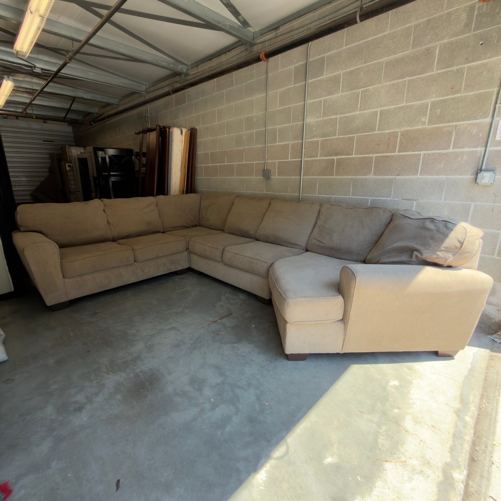 Tan fabric sectional sofa in storage unit, wide view