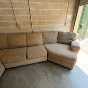Tan fabric sectional sofa, close-up of the chaise and rolled arm near the open garage door