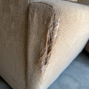 Tan fabric sectional sofa, detail close-up of the fabric tear on the armrest