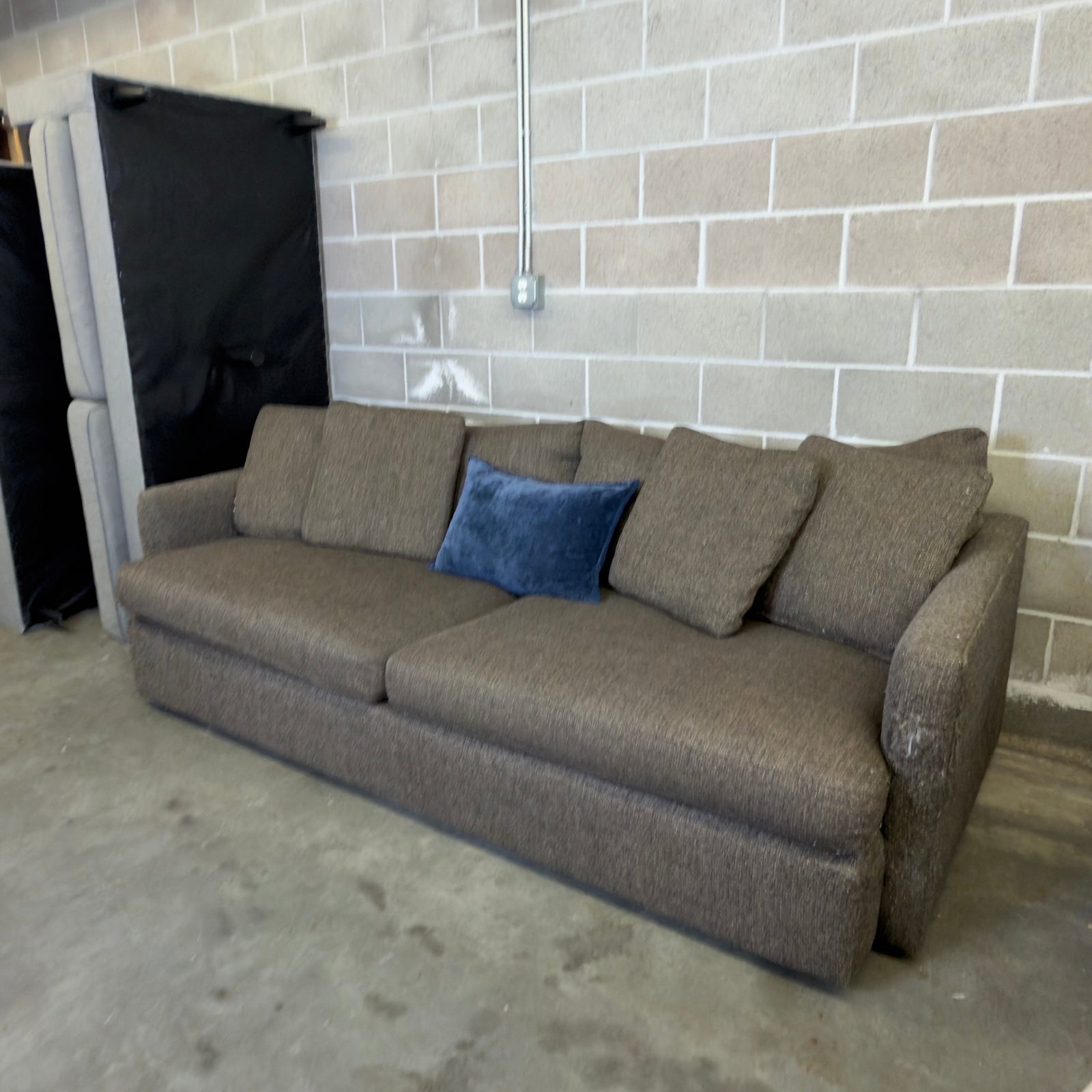 Brown Crate & Barrel tweed sofa, wide angle view in warehouse