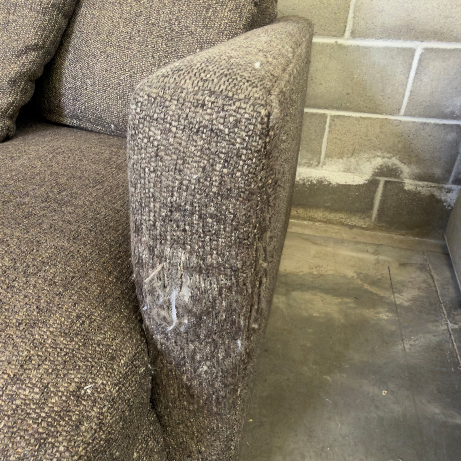 Close-up of worn and discolored fabric on the front-right arm corner