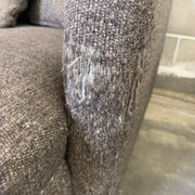 Macro close-up of frayed fabric on the front-right arm corner